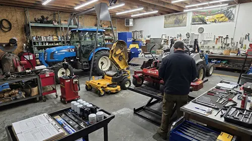 Technician servicing a mower on a lift in a professional repair shop